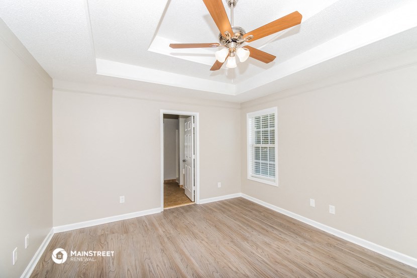 the spacious living room with ceiling fan and wood flooring