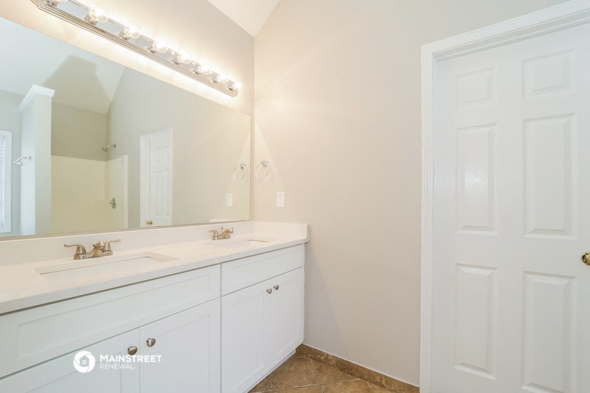a bathroom with white cabinets and a sink and a mirror