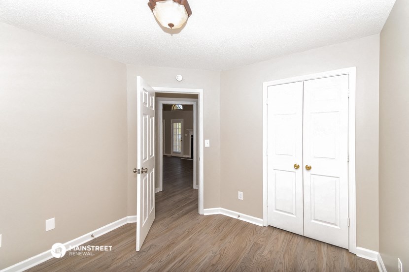 an empty room with white doors and a hallway with a door to a closet