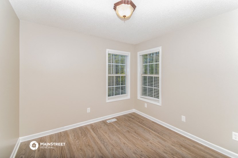 the spacious living room with hardwood flooring and two windows