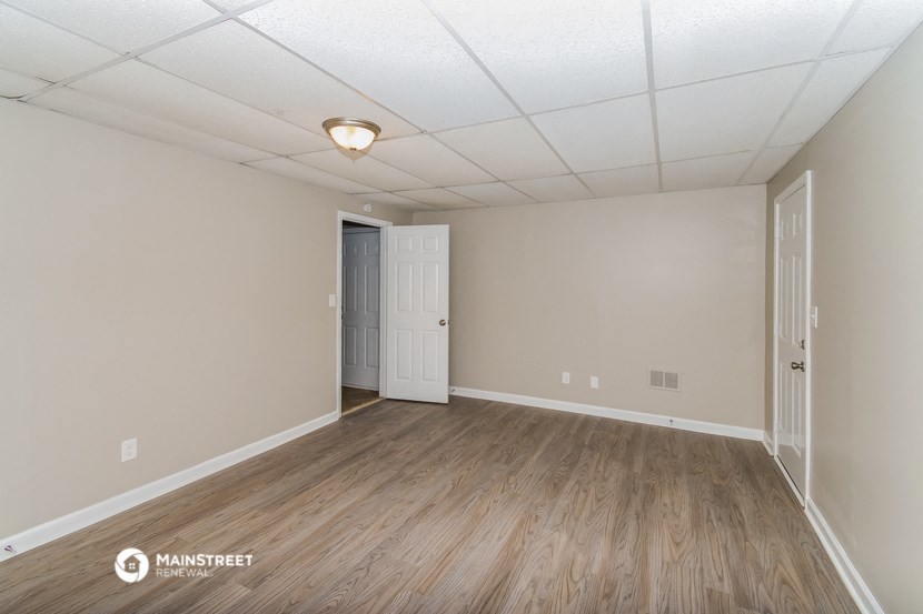 the spacious living room with wood flooring and white walls