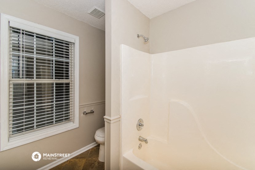 a bathroom with a shower and a toilet and a window