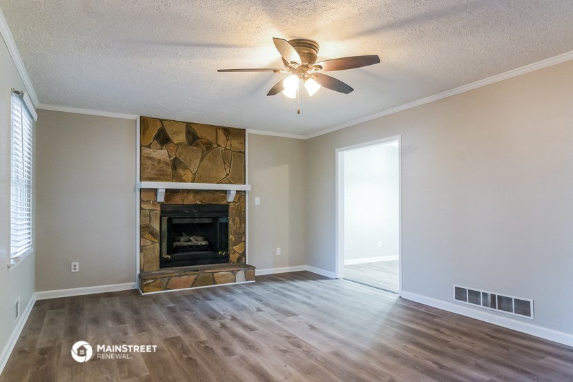 an empty living room with a fireplace and a ceiling fan