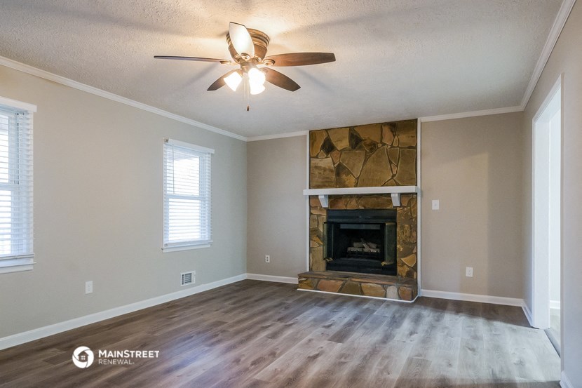 an empty living room with a fireplace and a ceiling fan