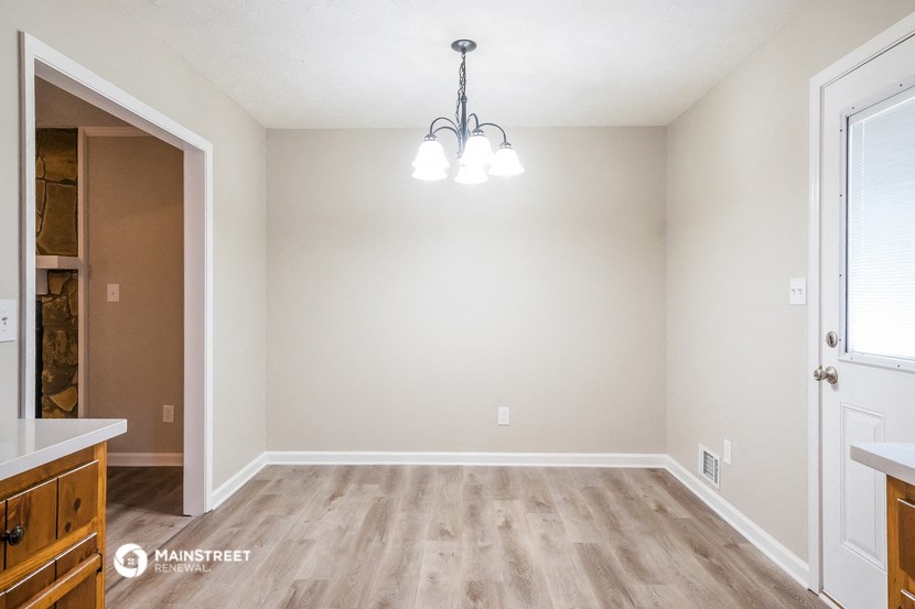 the spacious living room with wood flooring and white walls