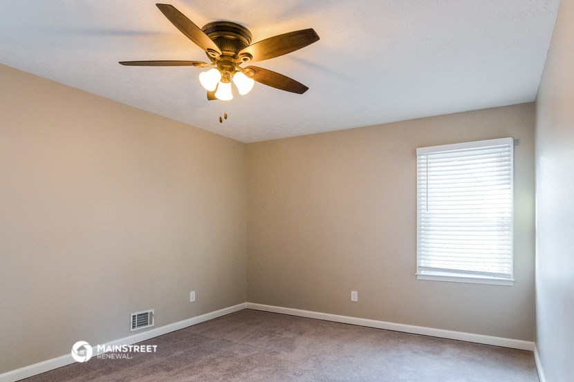 an empty room with a ceiling fan and a window
