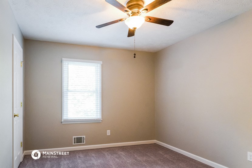 an empty room with a ceiling fan and a window
