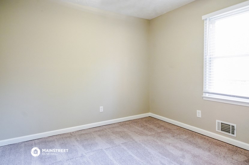 an empty room with vinyl flooring and two windows