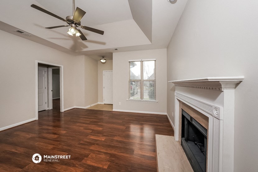 a living room with a fireplace and a ceiling fan