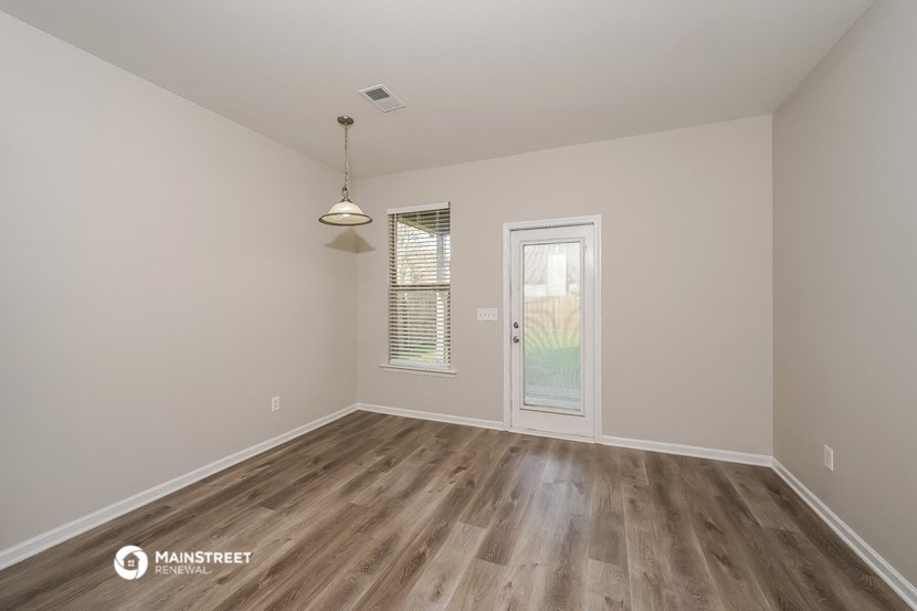 the spacious living room with wood flooring and a door to the backyard