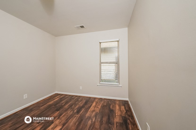 the upstairs bedroom with hardwood flooring and a window