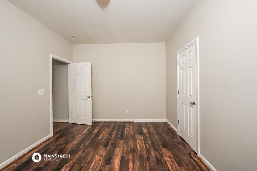 the living room of an apartment with wooden floors and white walls