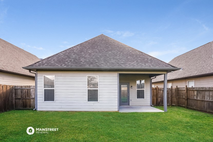 the backyard of a white house with a porch and green grass