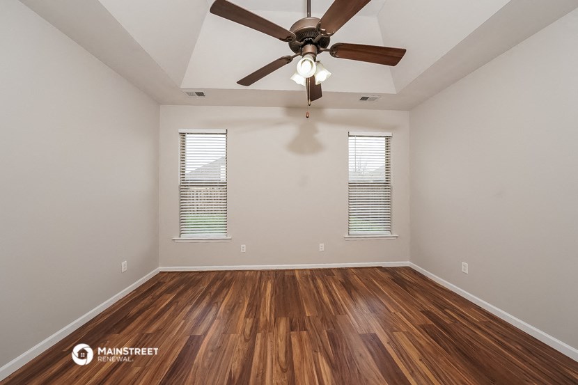 the spacious living room with wood flooring and a ceiling fan