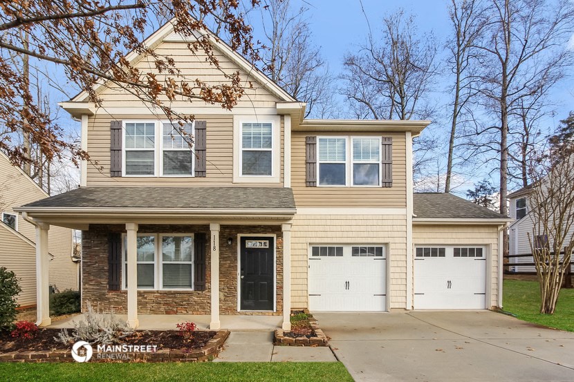 a tan house with two white garage doors