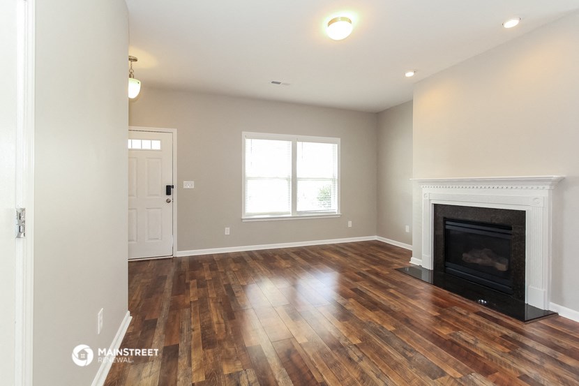 the living room of a house with a fireplace and wooden floors