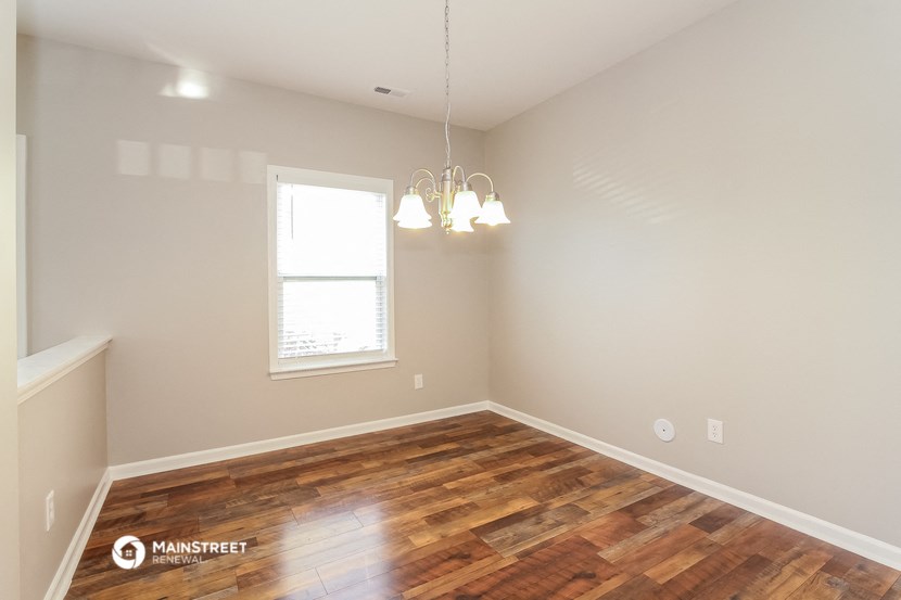 the spacious living room with wood flooring and a window