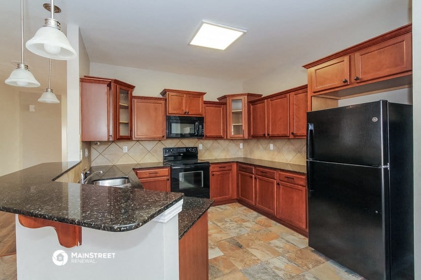 a kitchen with wooden cabinets and black appliances and granite counter tops