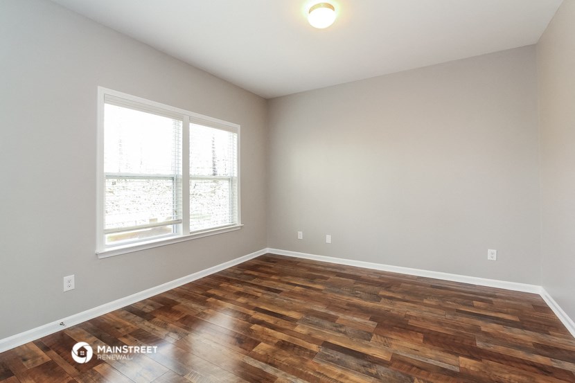 the spacious living room with wood flooring and a large window