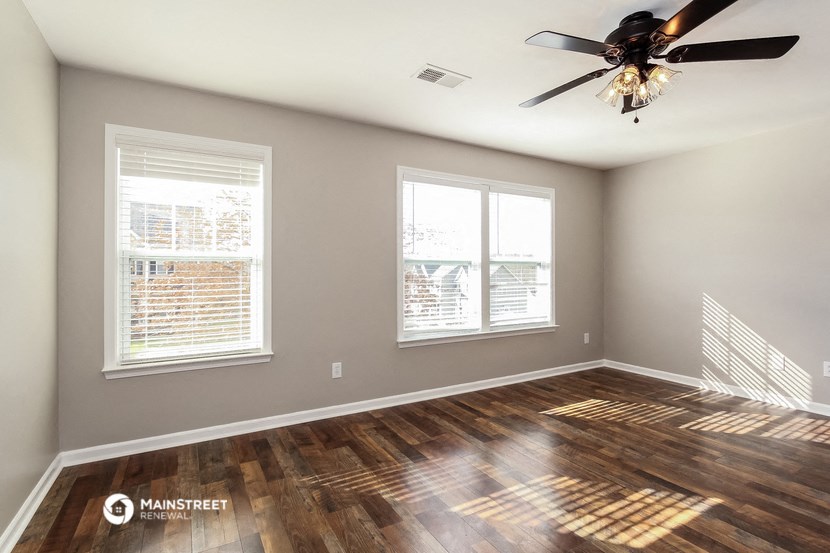 the living room of a home with a wood floor and a ceiling fan