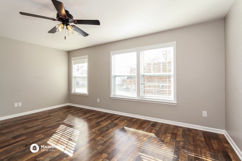 the spacious living room with hardwood floors and a ceiling fan