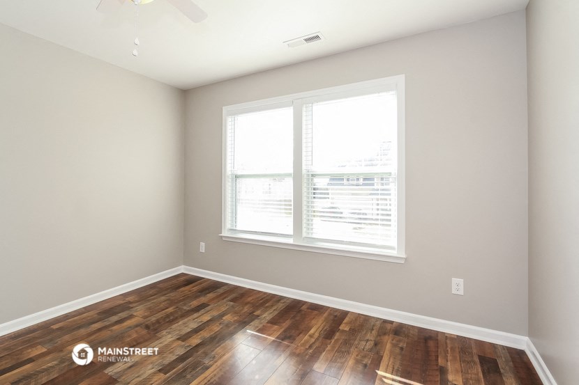 the living room of an apartment with wood floors and a large window