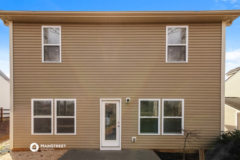 the exterior of a home with tan siding and white windows