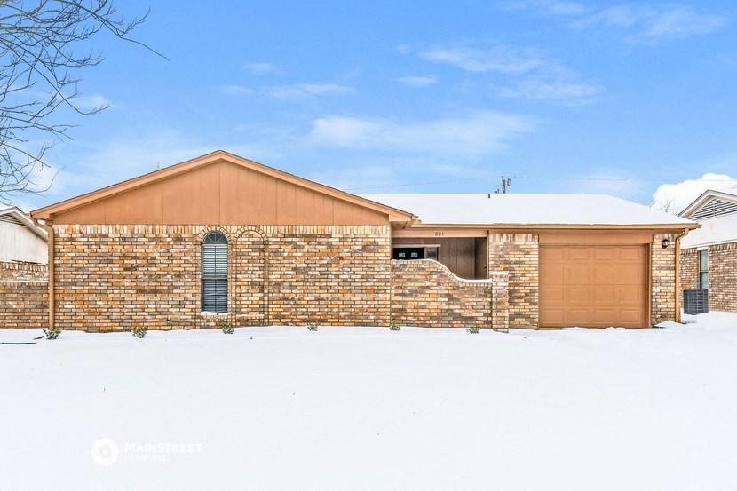 a brick house with a garage in the snow
