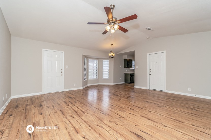 the living room and dining room with hardwood floors and a ceiling fan