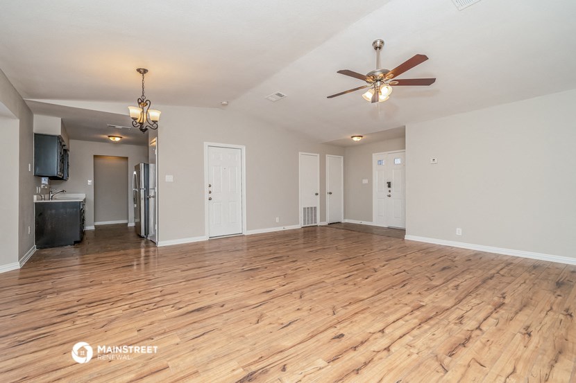 the living room and dining room with wood floors and a ceiling fan