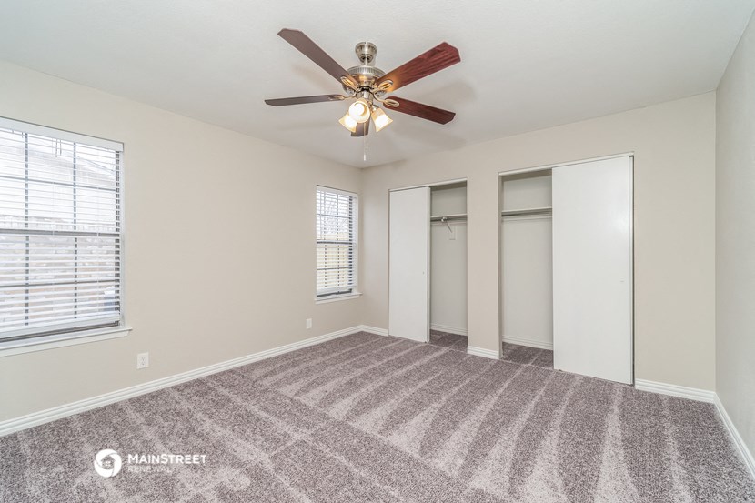 the spacious living room with ceiling fan and mirrored closets