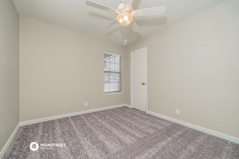 the spacious living room with ceiling fan and carpet