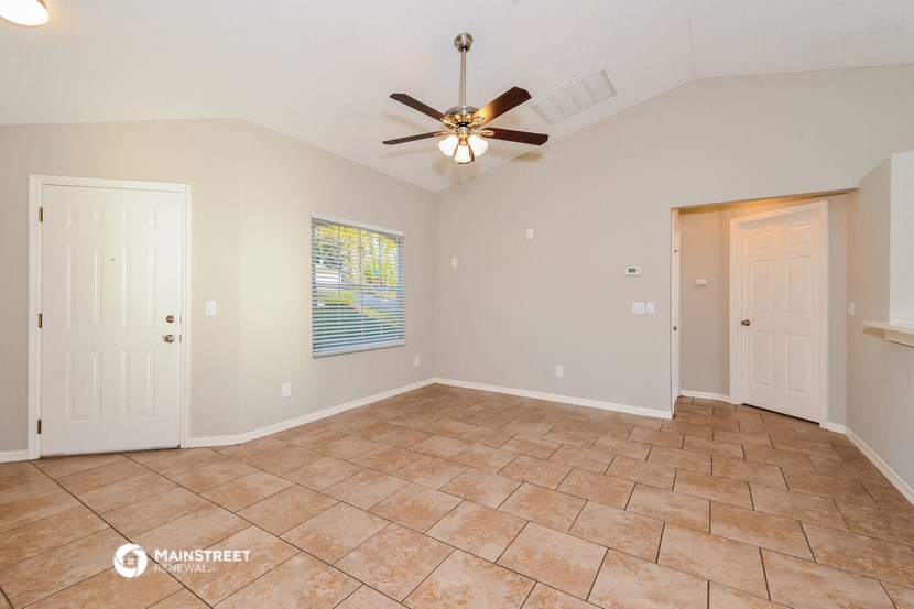 the living room of an empty home with a ceiling fan