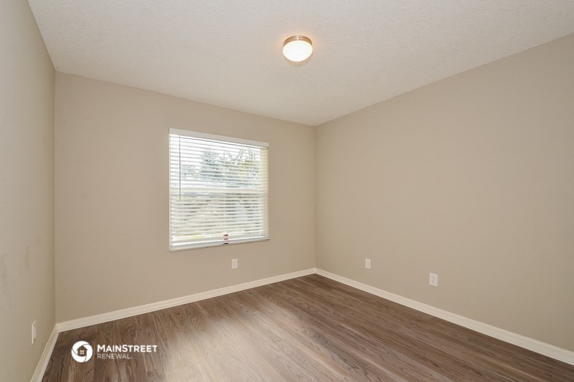 the spacious living room with hardwood flooring and a window
