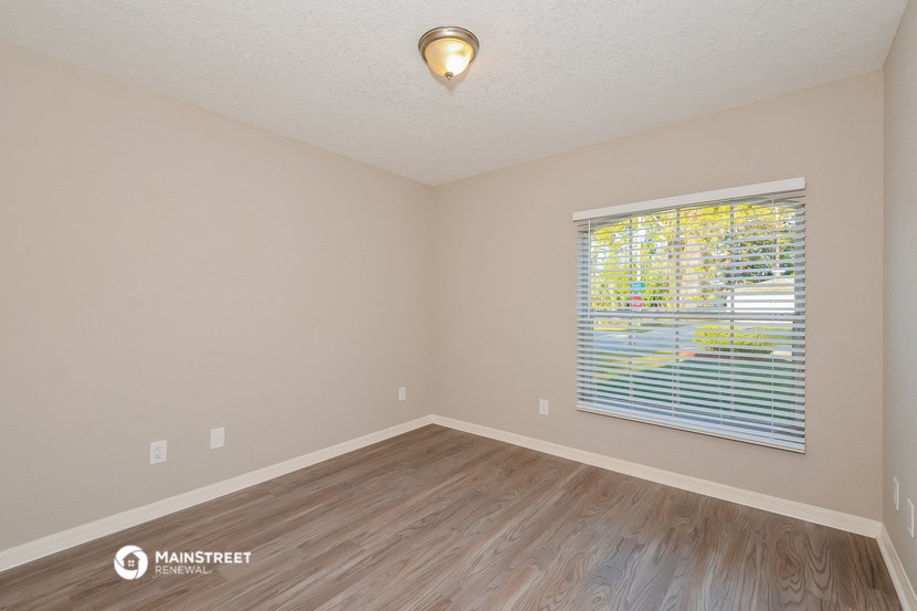the spacious living room with wood flooring and a large window