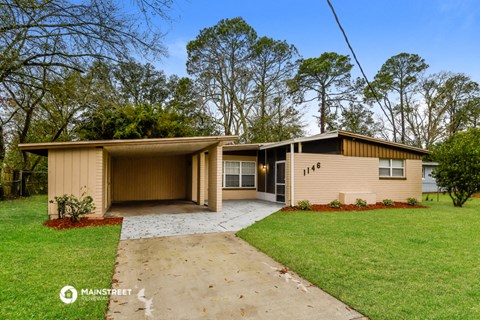 a yellow house with a driveway and a lawn