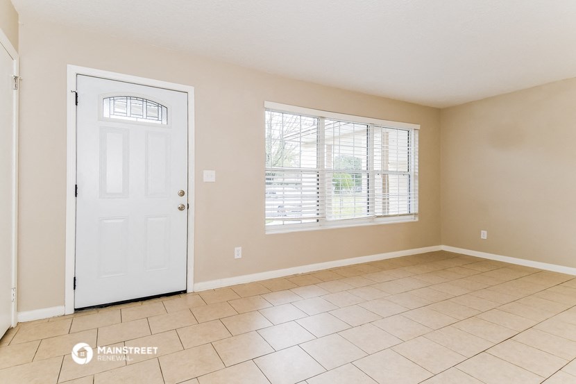 an empty living room with a white door and a window