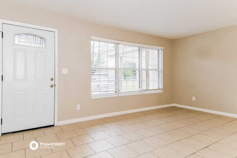 an empty living room with a white door and a large window