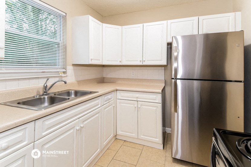 a kitchen with white cabinets and a stainless steel refrigerator