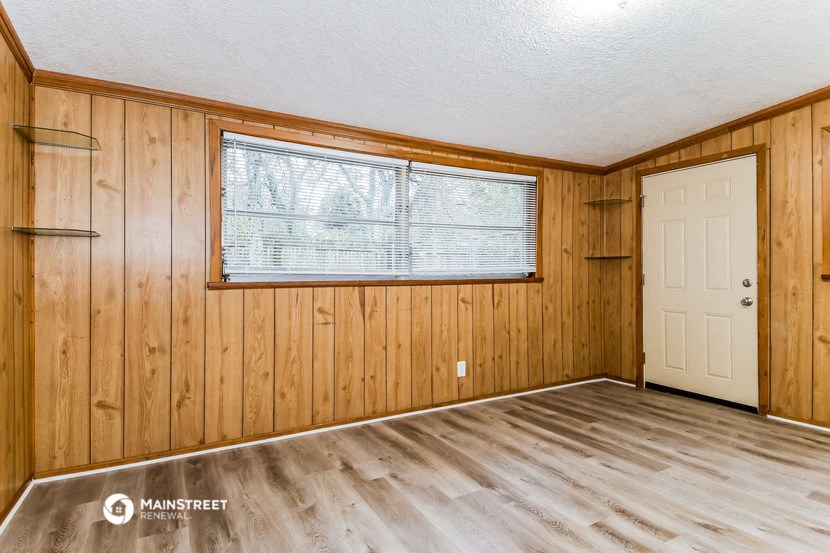 a bedroom with wood floors and a window and a door