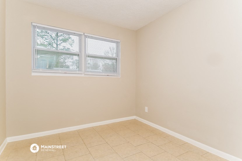 an empty room with a window and a tiled floor