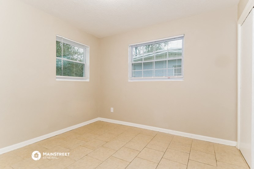 the living room of a home with a tiled floor and two windows