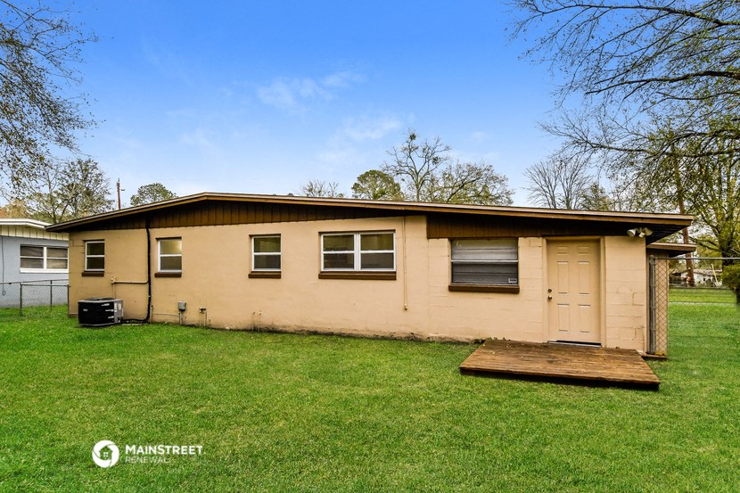 a small tan house with a garage and a grassy yard
