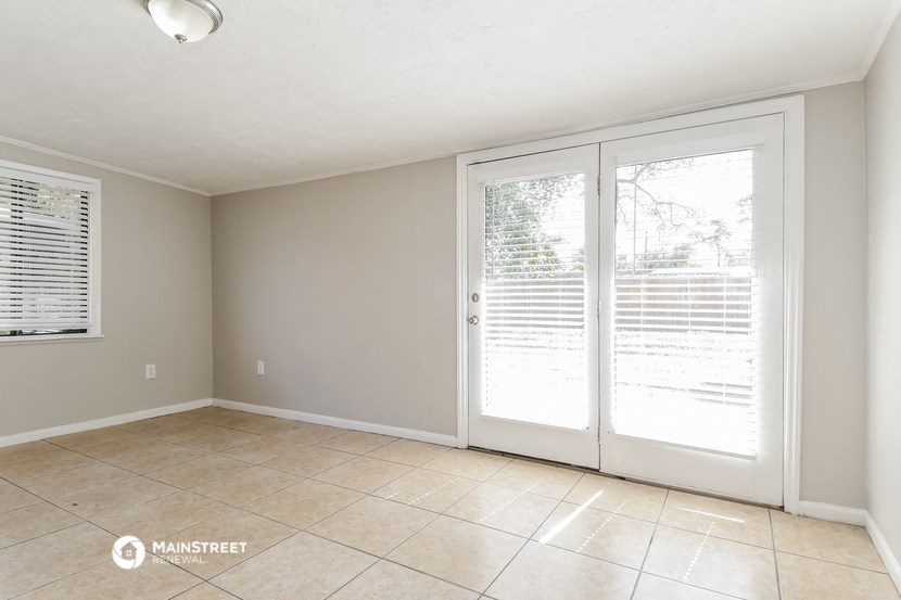 an empty living room with sliding glass doors to a patio