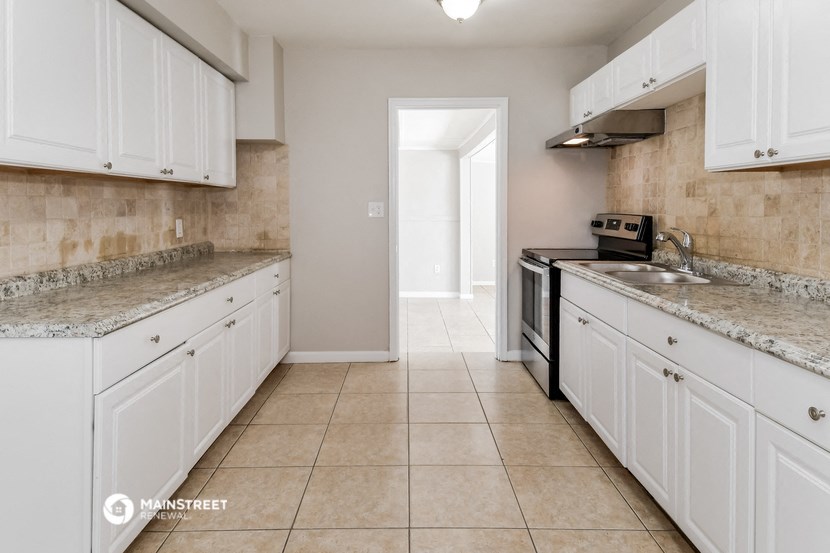 a kitchen with white cabinets and a stove and a sink