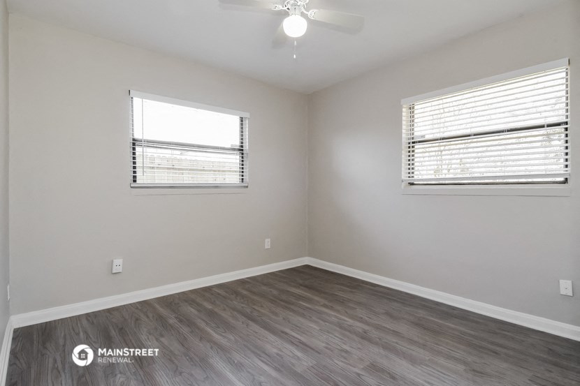 the living room of an apartment with wood flooring and a ceiling fan