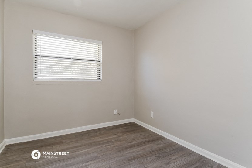 the interior of a bedroom with wooden floors and a window