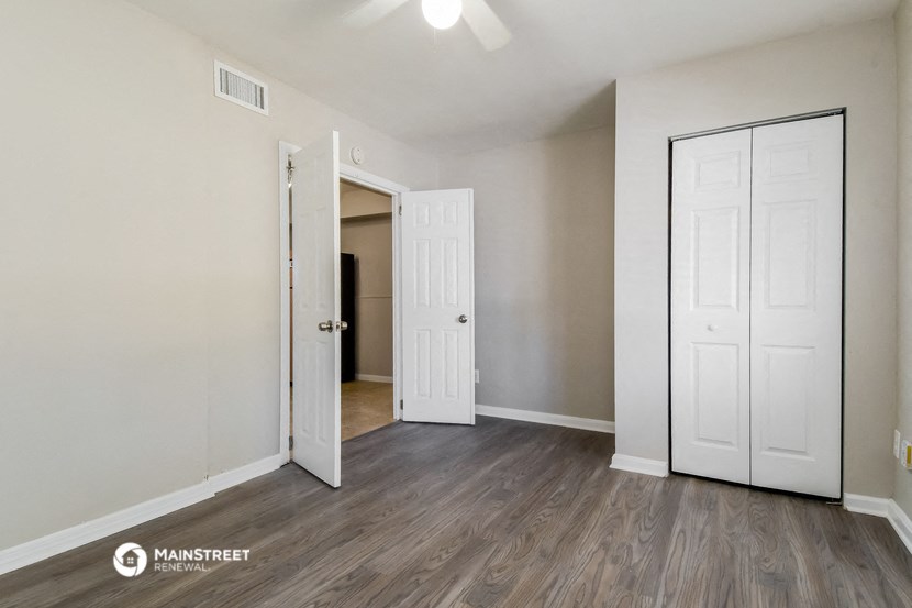 the living room of an apartment with white doors and wood flooring