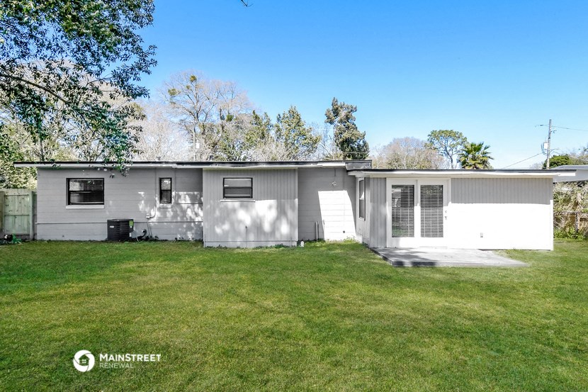 a white mobile home in a grassy yard with trees