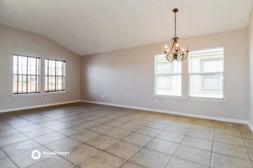 an empty living room with a chandelier and windows